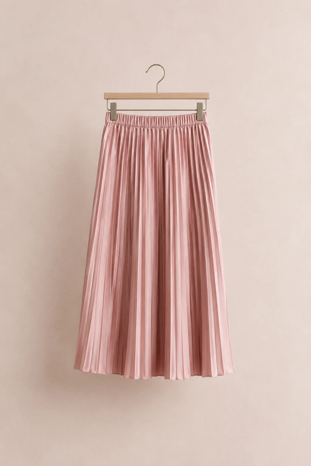 Blush pleated satin midi skirt hanging from a clip hanger